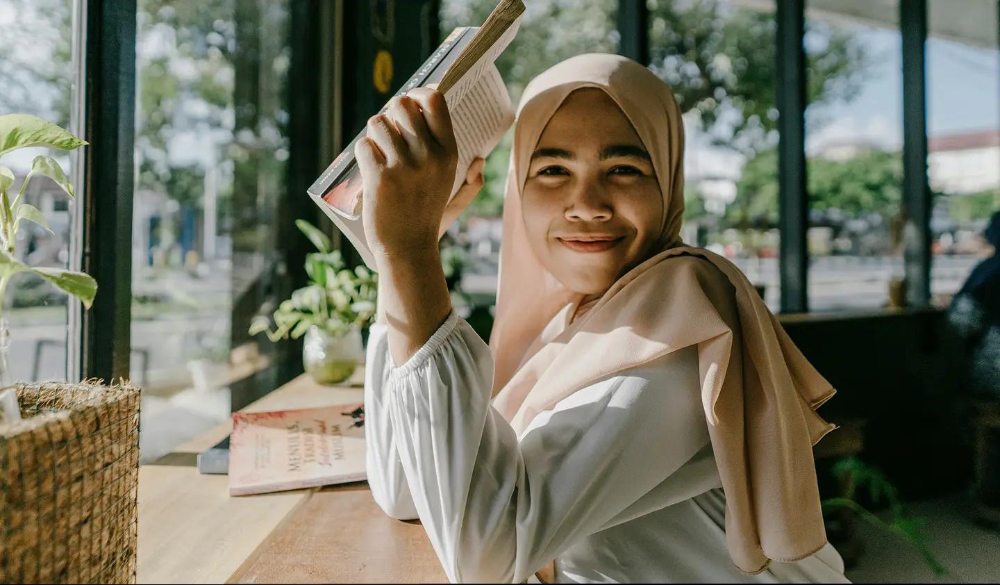 A university student smiling with a book